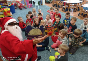 Mikołaj czyta dzieciom opowieść świąteczną.